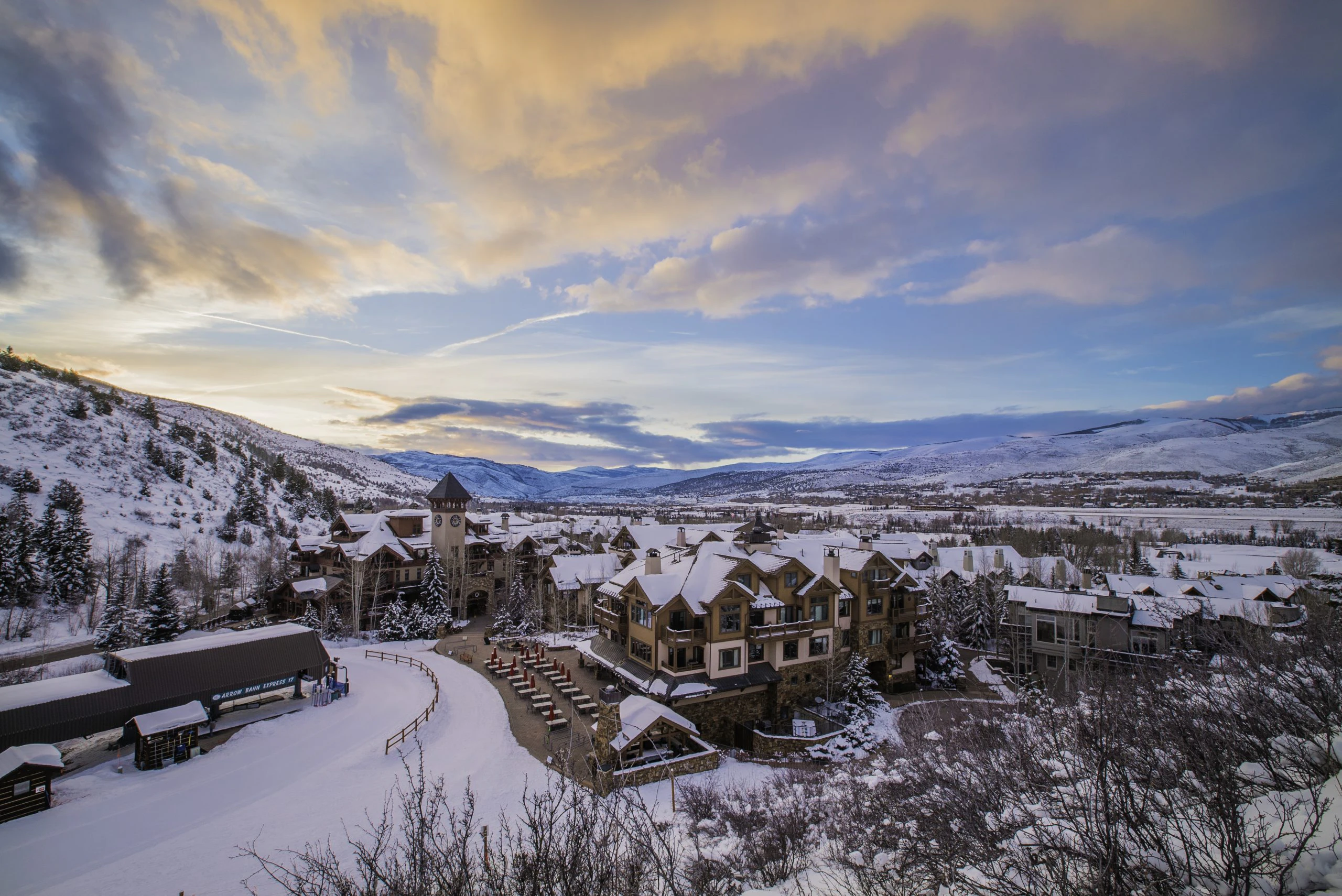 Winter view of luxury vacation rentals in Arrowhead Village, Beaver Creek, with snow-covered rooftops and mountain scenery at sunset.