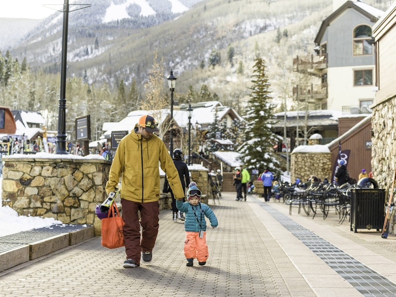 Father and son holding hands, walking through Beaver Creek Village in Beaver Creek Resort