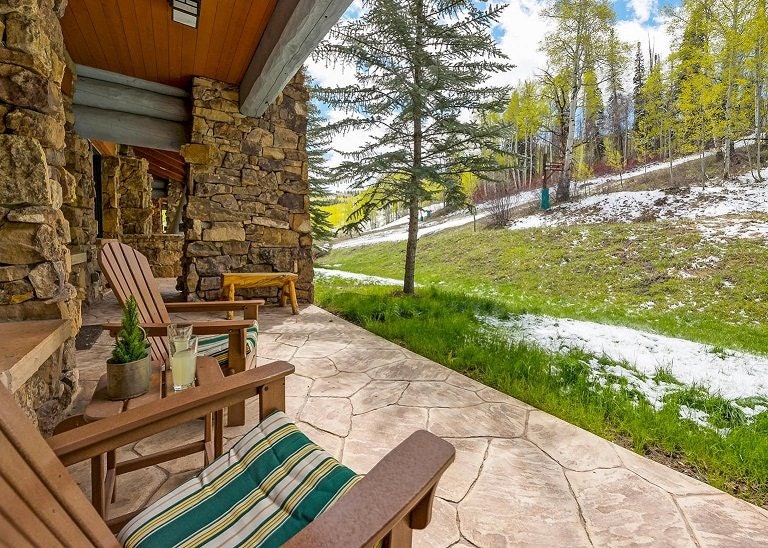 Patio with deck chairs looking out onto a slope and forest at a luxurious Beaver Creek ski in ski out lodging.