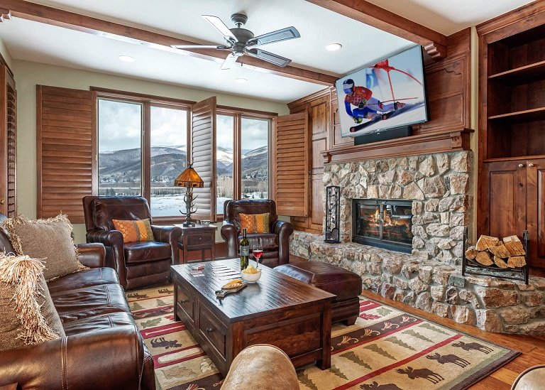 Beaver Creek condo rental lounging area with wooden finishings, leather couches and fireplace.