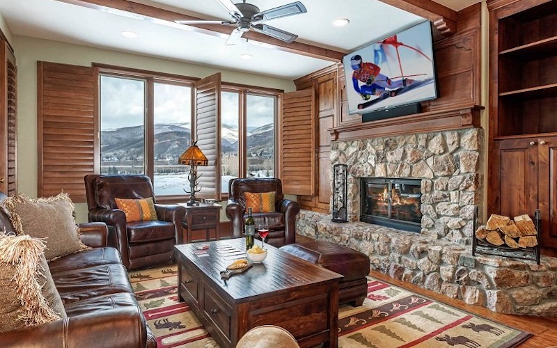 Beaver Creek condo rental lounging area with wooden finishings, leather couches and fireplace.