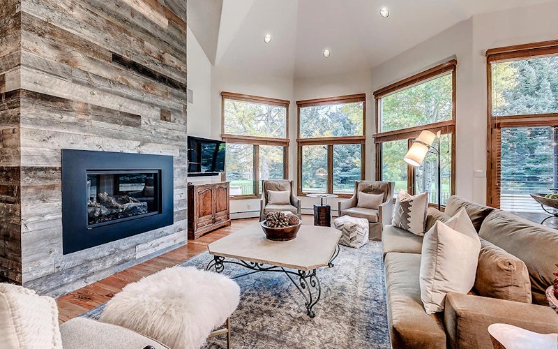 Luxurious lounge of a home rental in Beaver Creek resort with large modern fireplace and large windows.