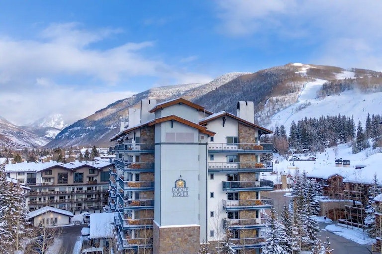 Vail vacation rental Lodge Tower building from the outside with magnificent mountain views in the background.