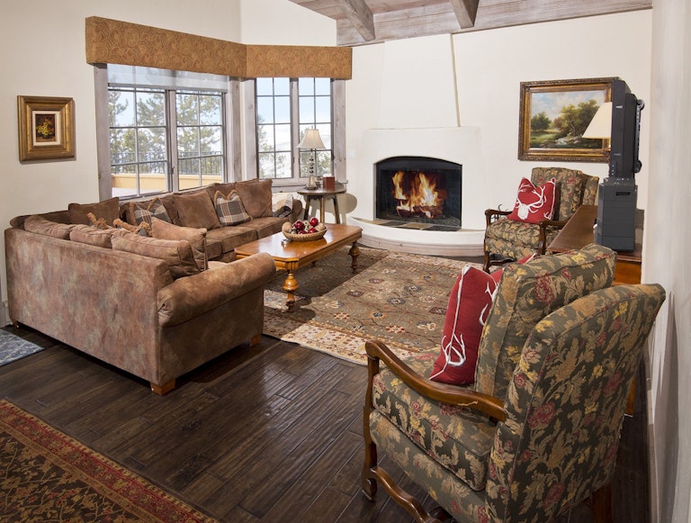 Vail ski-in/ ski-out rental option lounge with wooden floor, large couches and a roaring fireplace.