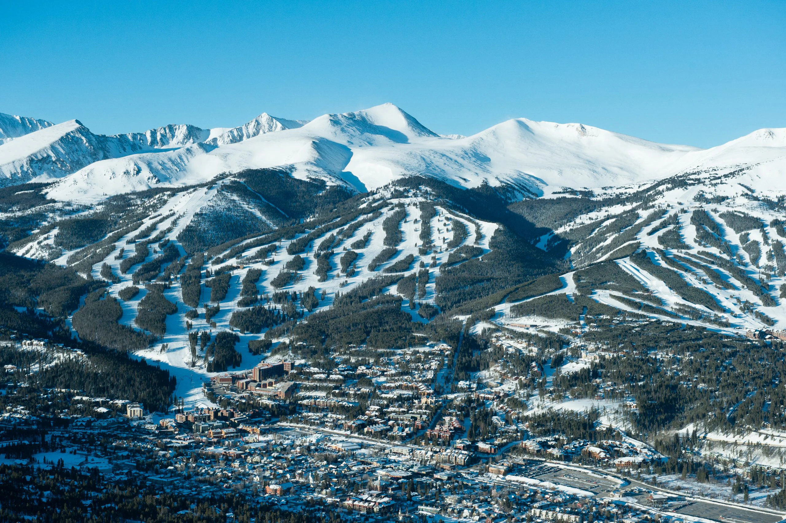 Aerial view of Breckenridge ski resort with snowy trails and mountain town below, showcasing the charm and layout in the Vail vs Breckenridge comparison.