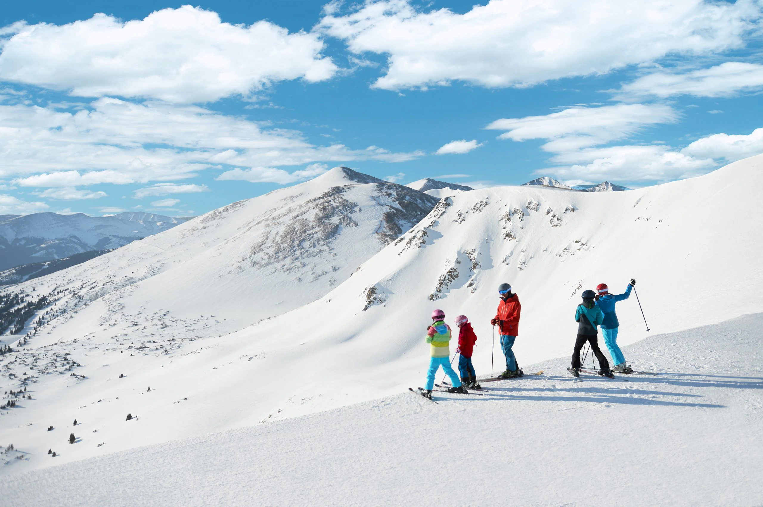 Skiers enjoying a sunny day on the slopes, showcasing the scenic terrain and family-friendly atmosphere typical of Colorado resorts like Vail and Breckenridge.
