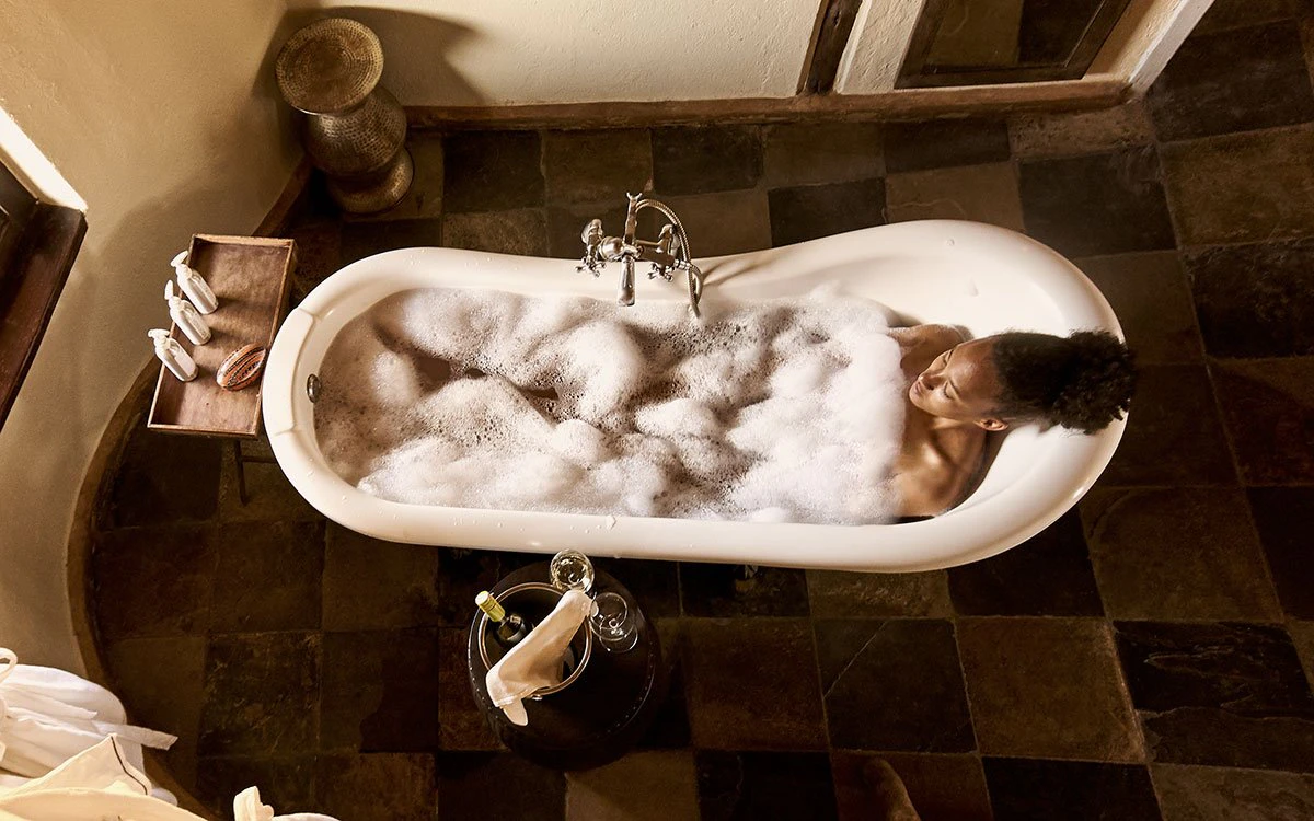 A female guest indulges in a relaxing bathtub after a day on safari from Tawi Lodge