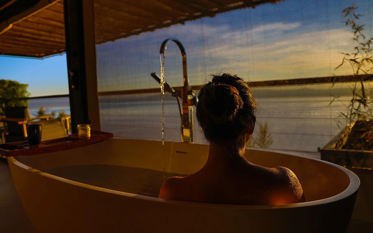 A female guest enjoys a relaxing bath as she gazes over Lake Nakuru at sunset