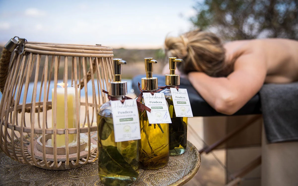 A guest relaxes during an indulgent al fresco massage, with an assortment of essential oils in the foreground