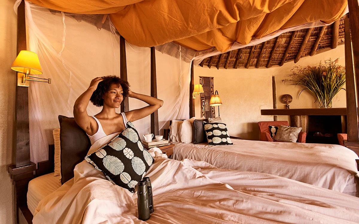 A female guest awakens in her bed in one of Tawi Lodge's luxurious bedrooms