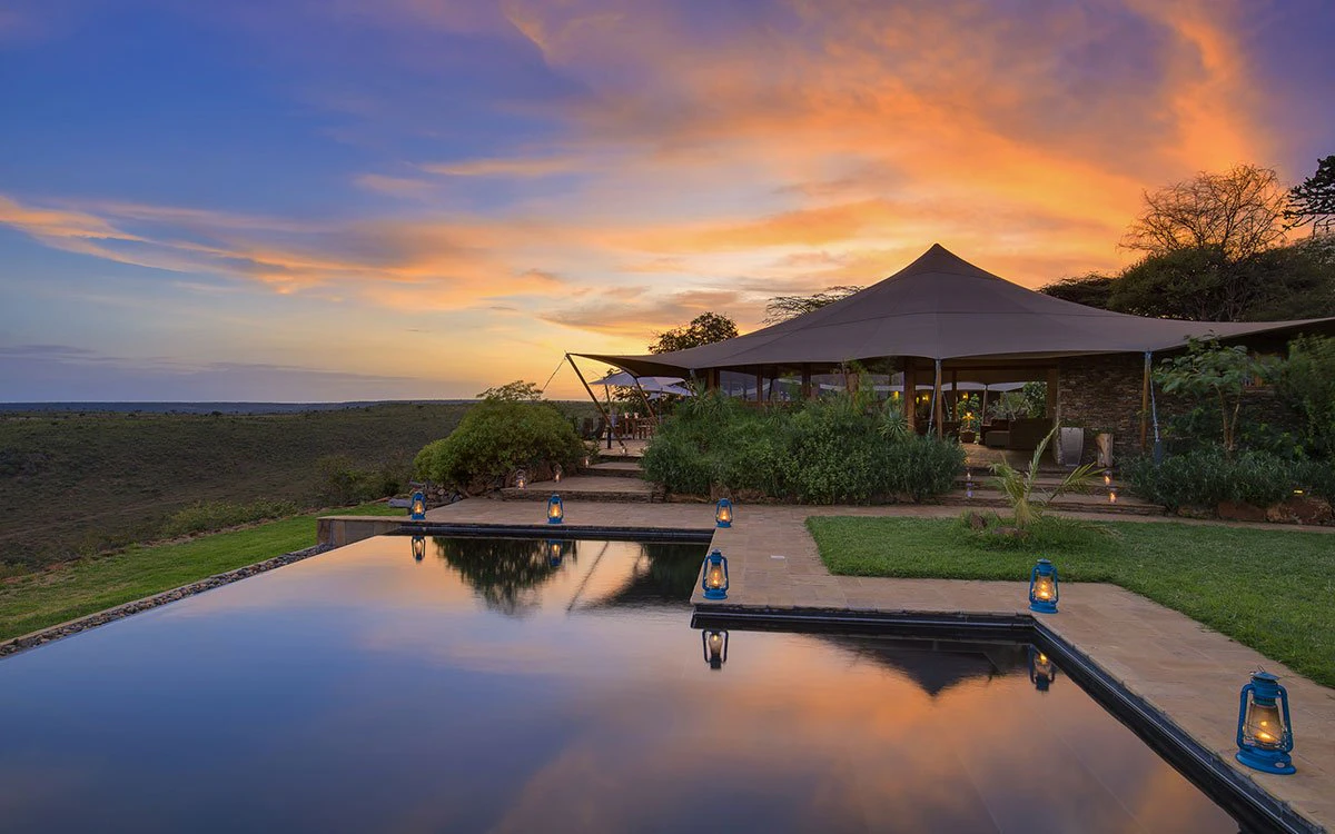 Exterior view of Loisaba Tented Camp's infinity pool at sunset, with the lodge in the background