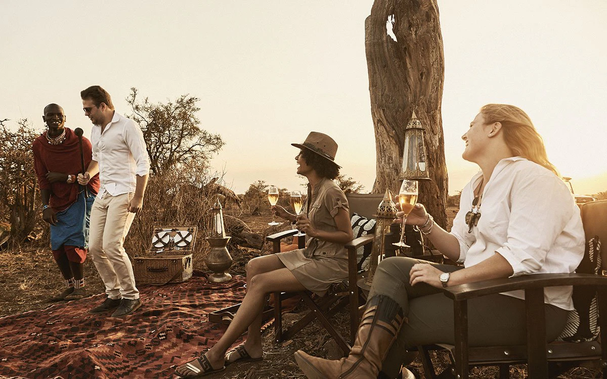 A group of guests enjoy an al fresco drink with their guide as the sun begins to set behind them