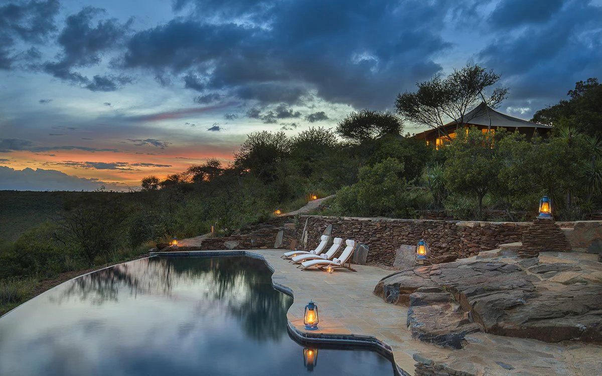 A sunset image of Loisaba's second infinity pool with deck chairs set up invitingly