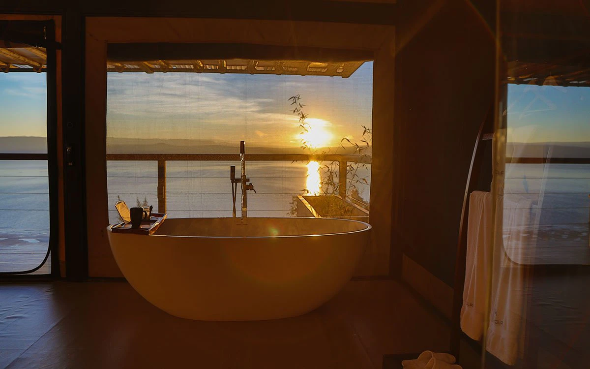 The large bathtub inside the en suite bathroom at The Cliff with a view of a stunning sunset over Lake Nakuru