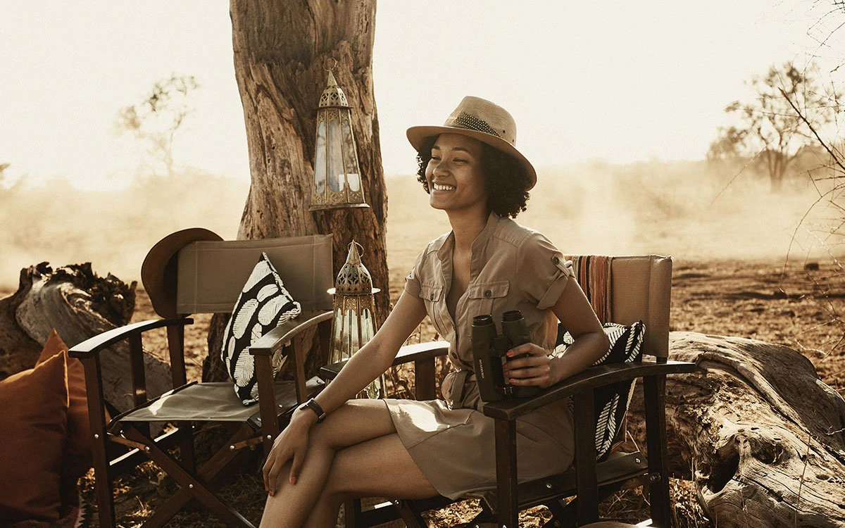 A female guest enjoys sitting and engaging with the surrounding wildlife with her binoculars in hand