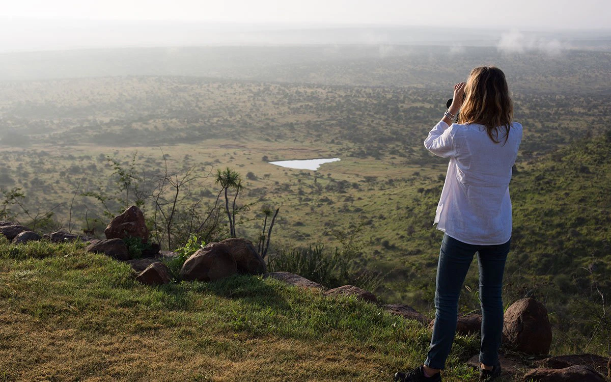 A female guest views the spectacular view from Loisaba Tented Camp with her complimentary binoculars