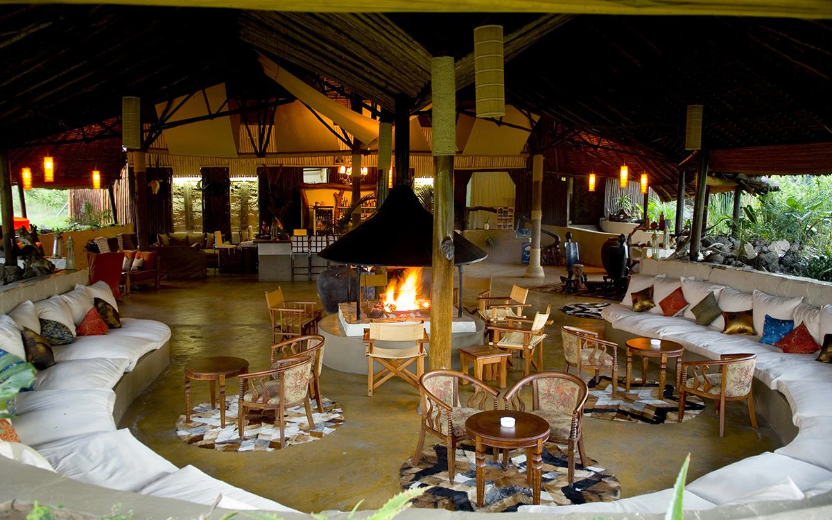 The communal area at Mbweha Camp with a large white wraparound sofa and a fire in view