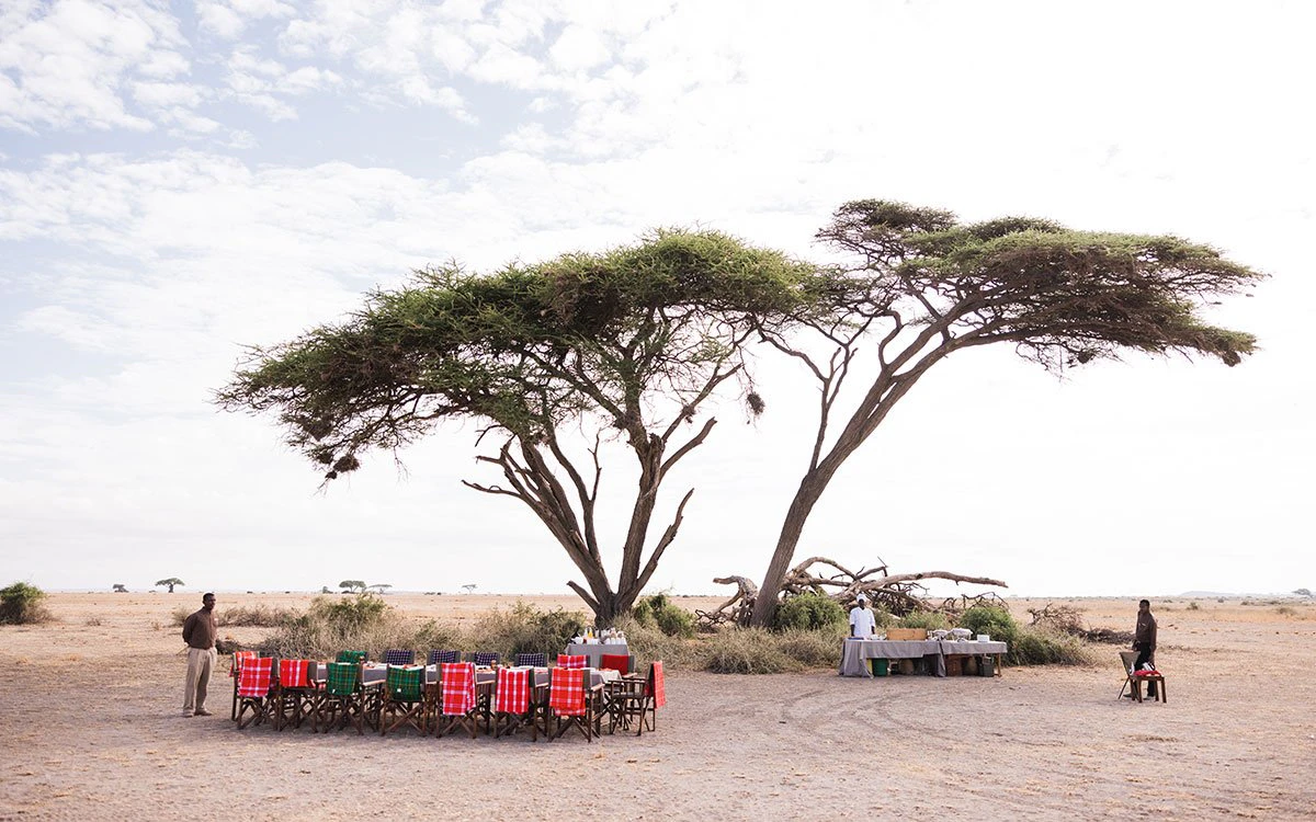 Three members of the team at Tortilis Camp prepare an al fresco lunch under a tree
