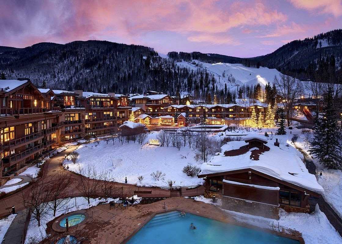 Manor Vail Lodge illuminated during a snowy evening, offering a cozy retreat