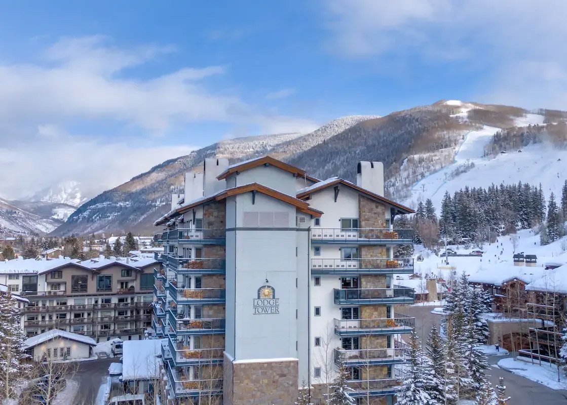 Lodge Tower Vail gleaming under the evening sun, with the magnificent Vail mountains in the distance