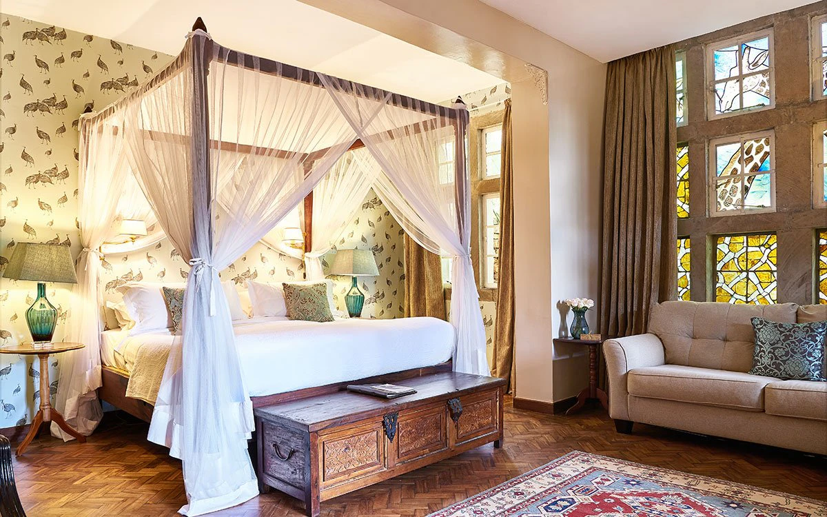 Internal view of one of the luxury suites at Giraffe Manor with a large comfortable bed and sofa