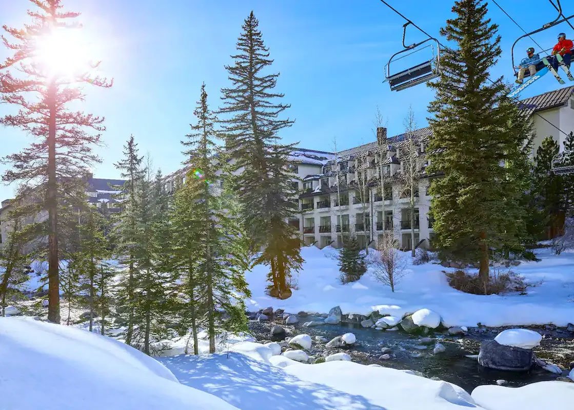 Elevated view of Grand Hyatt Vail, enveloped by snow-covered peaks and evergreen forests.