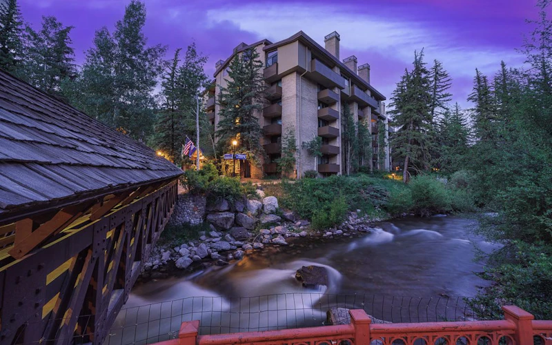Picturesque night view of Vail's Mountain Haus luxury rental beside a creek in Valleyside.