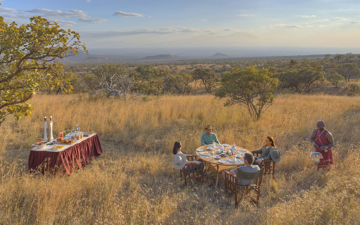 A quartet of guests enjoy an al fresco breakfast in the bush