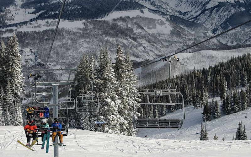 A young family riding the chair lift on their way to enjoy skiing in Vail Resort A young family riding the chair lift on their way to enjoy skiing in Vail Resort