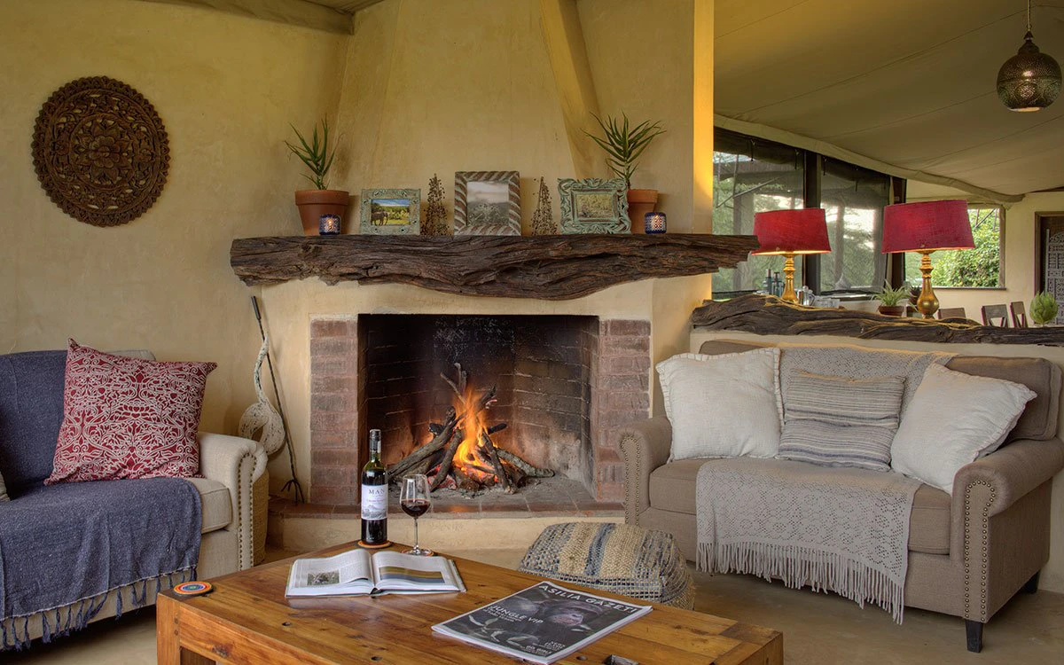 Interior view of the communal lounge at Ol Pejeta with a fire going and a bottle of red wine