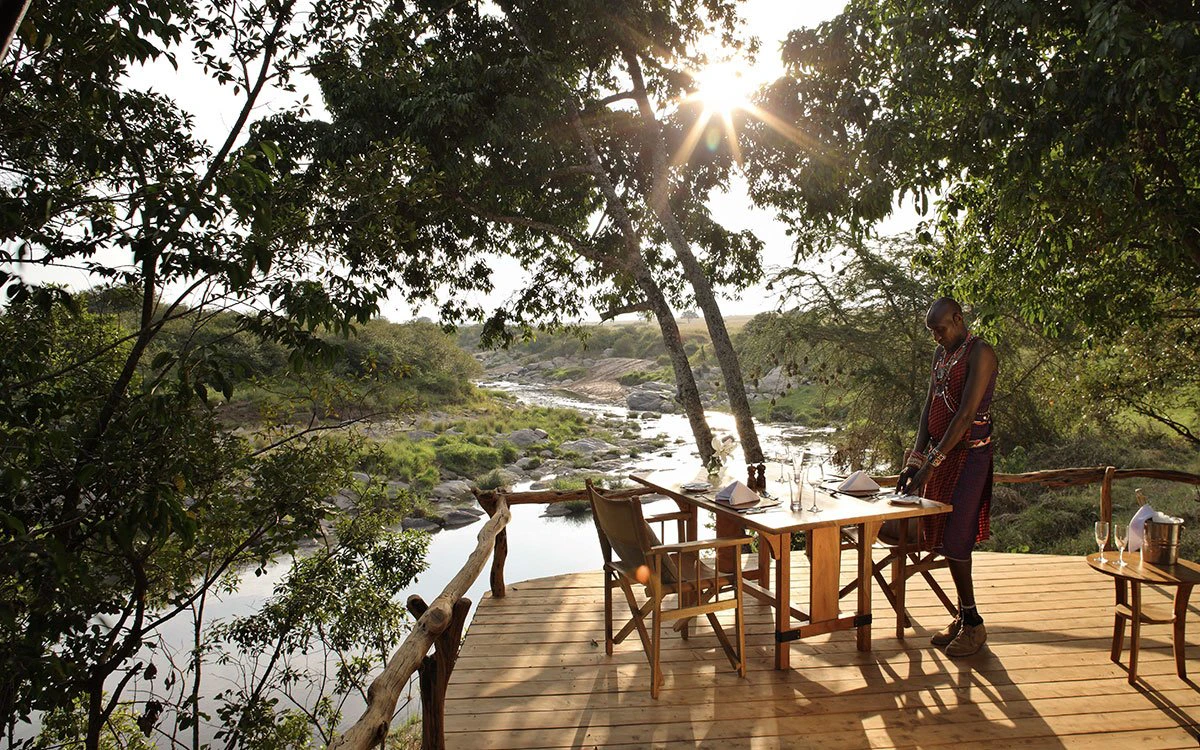 A table is being set for dinner on the private deck overlooking the Talek River