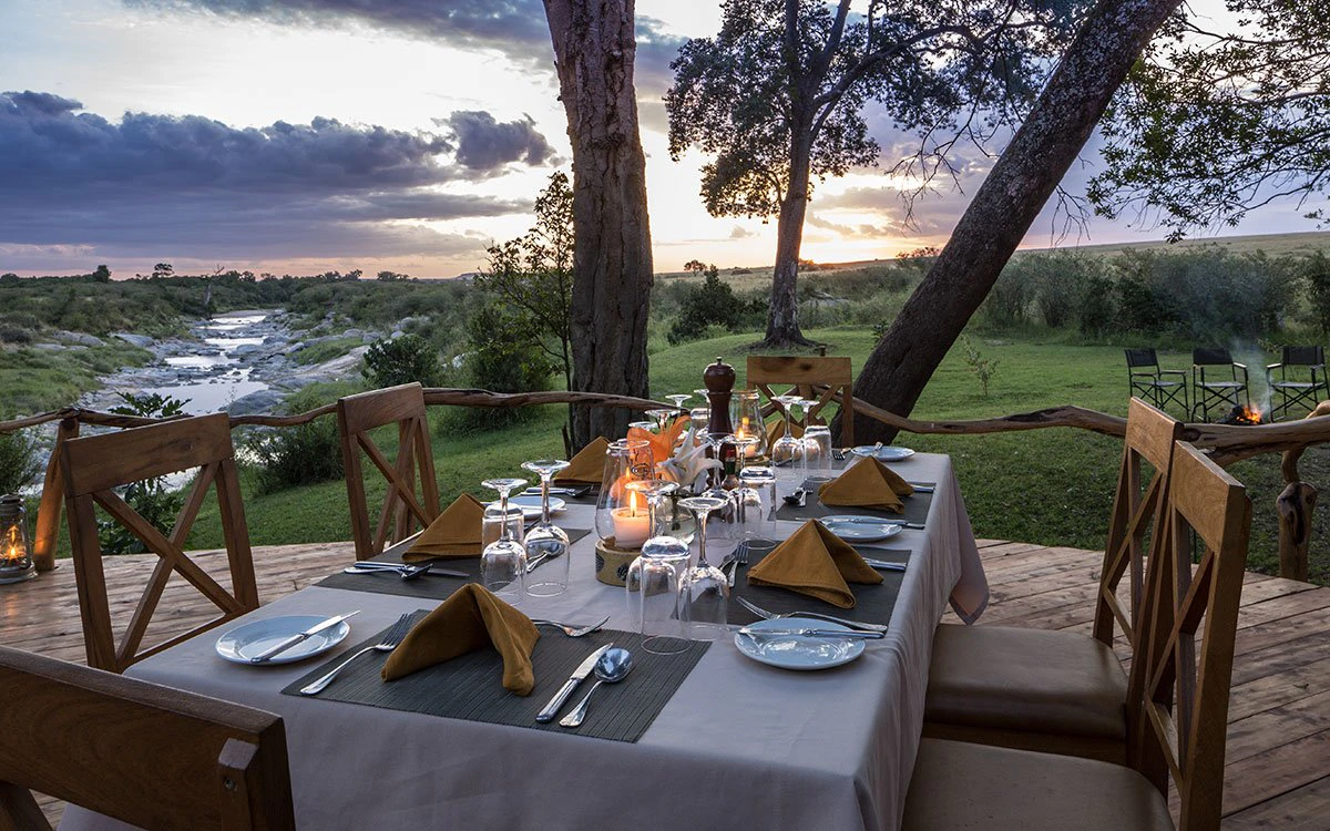 A set table is ready for guests to enjoy a sunset dinner on the deck at Rekero Camp