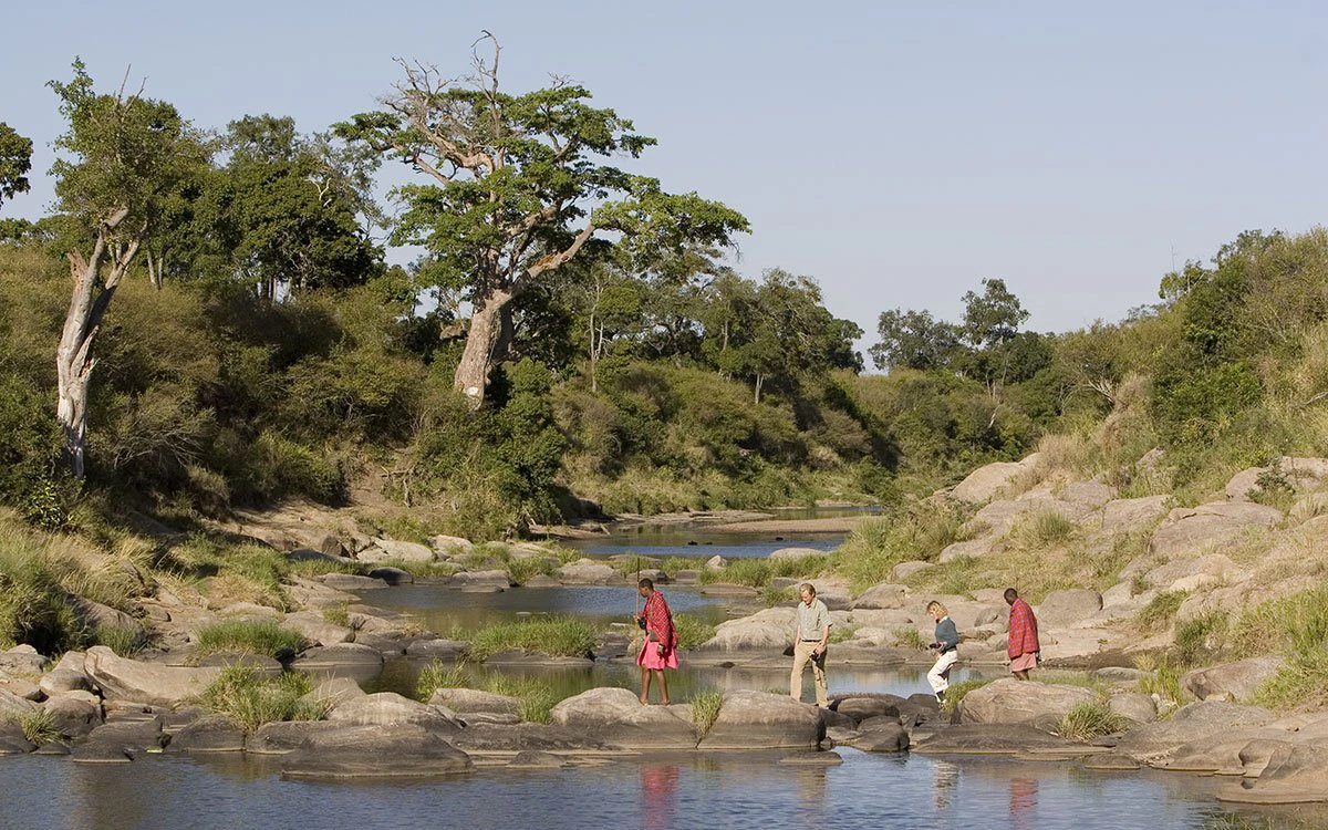 Two guests and their Maasai guides cross the river on foot