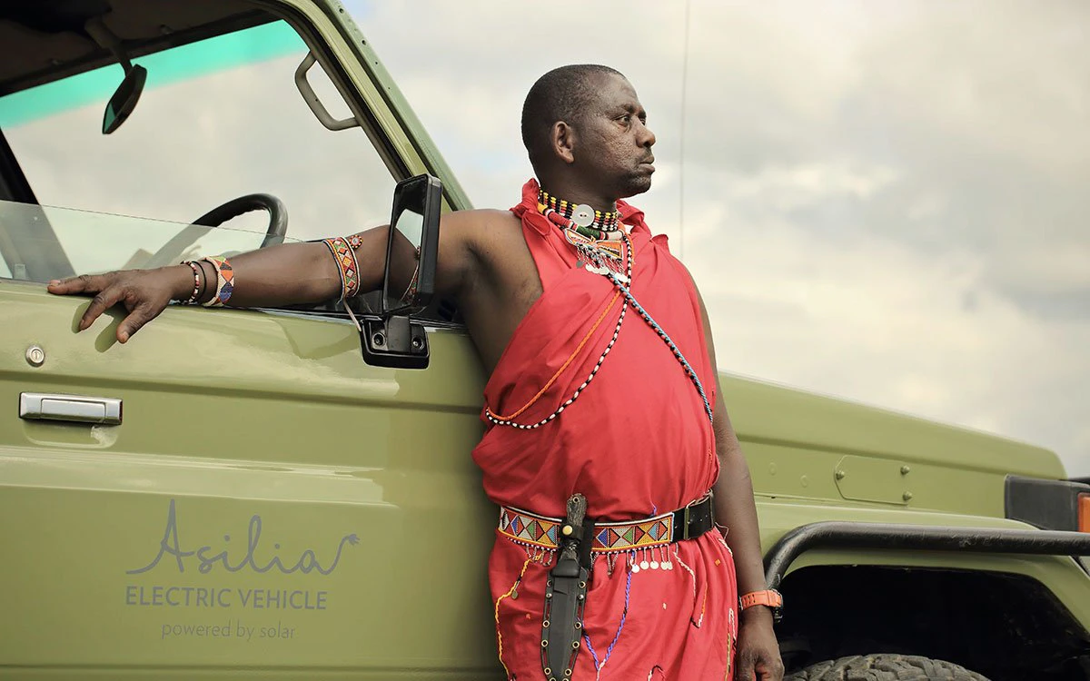 An experienced guide rests against the side of one of the safari vehicles before heading out on a game drive