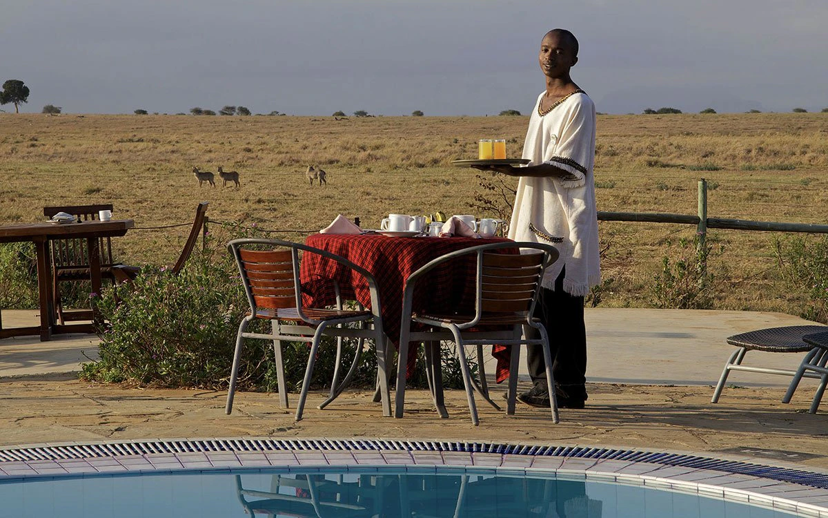 A member of the team at Aruba sets up breakfast by the pool with a beautiful view in the background