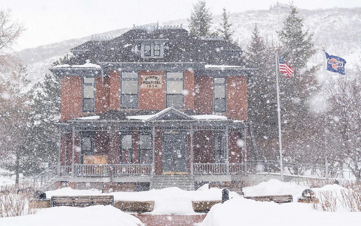 A historic building in downtown Park City with snow falling in the foreground.