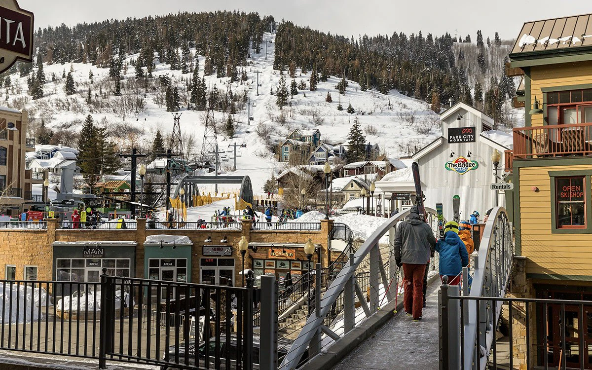 Wide view of the base of Park City mountain, with skiers crossing the bridge.