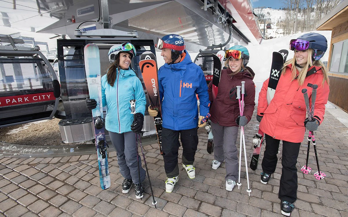 A group of friends make their way through downtown Park City holding their ski equipment.