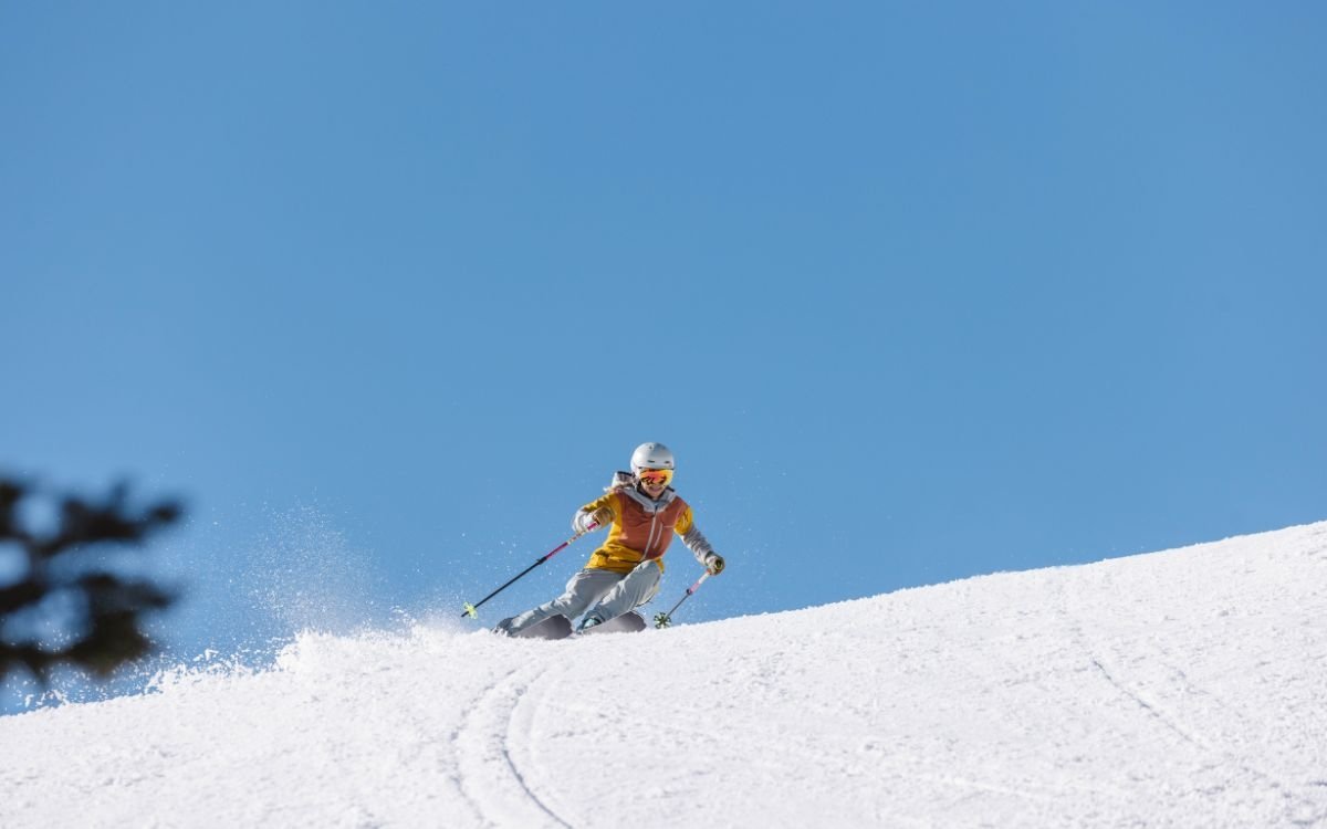 A single female skier expertly turns down the slopes on a sunny day at Deer Valley.