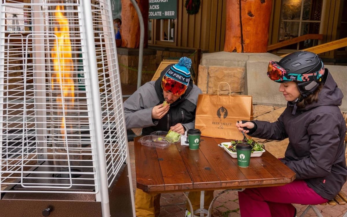 Two skiers enjoy a takeaway meal outdoors from Deer Valley Etc.