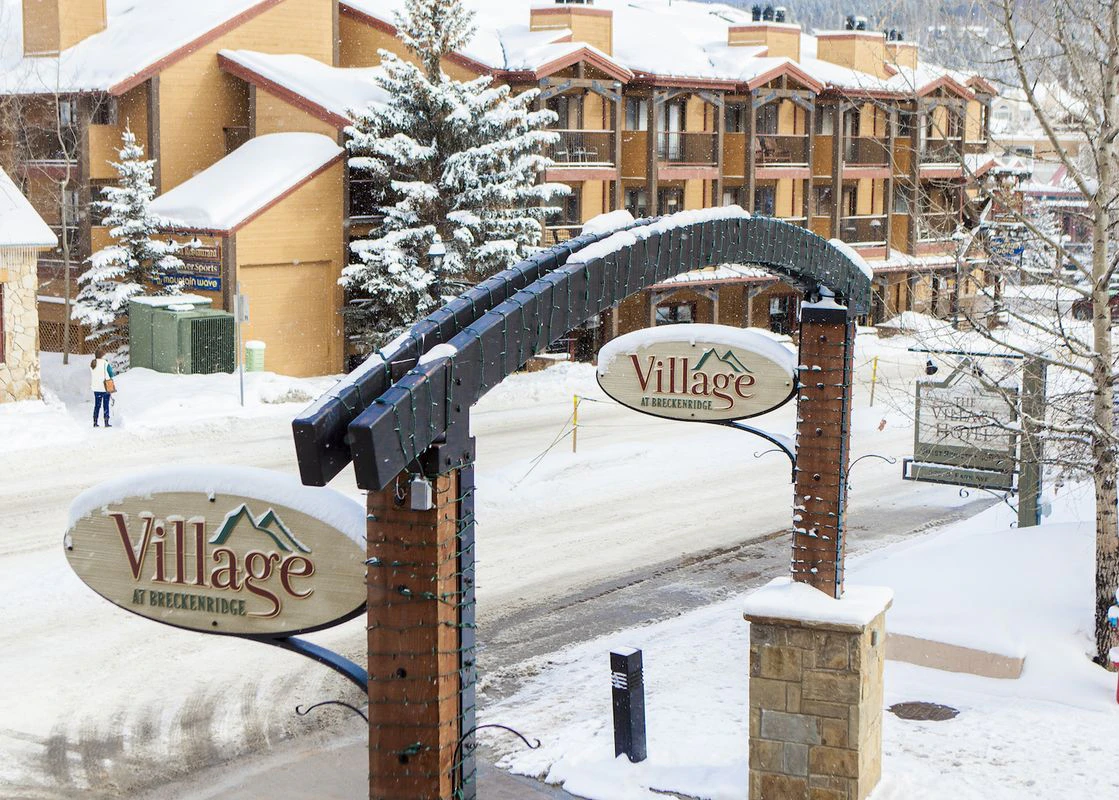 The signage indicating the entrance to the Village at Breckenridge, with snow falling in the background.