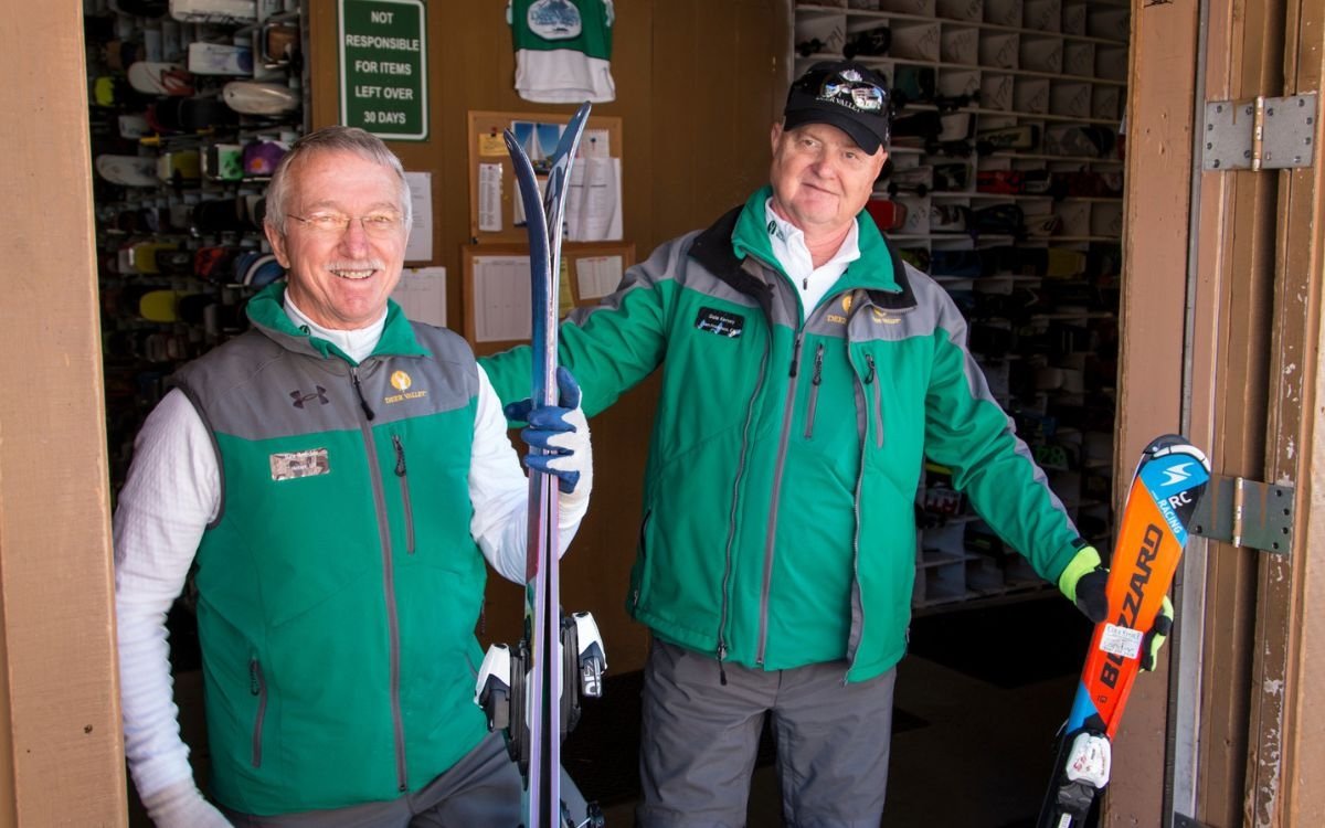 Two members of the ski valet team hold ski equipment available for rent.