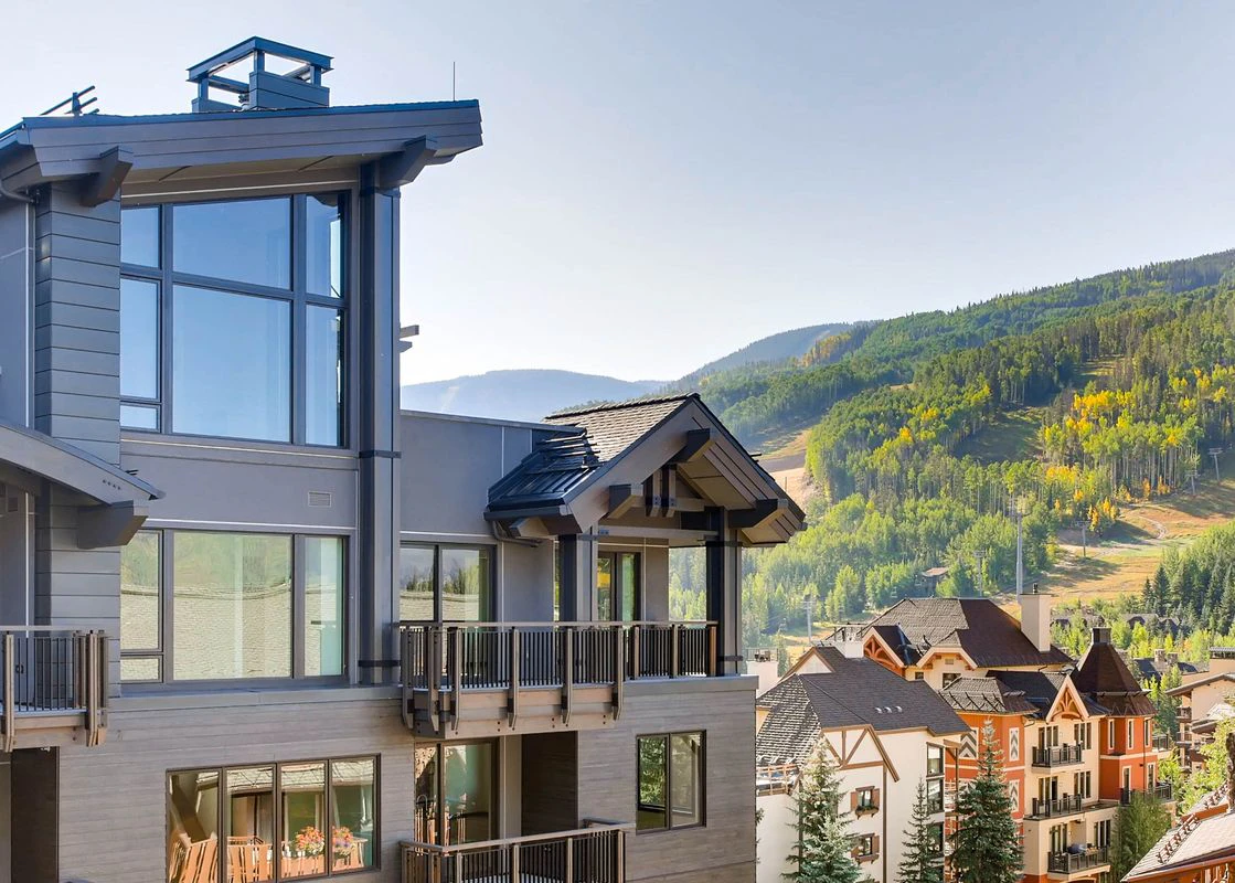 The exterior of the Lion in Vail with a sunny, summer mountain backdrop.