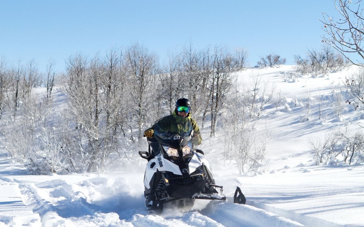 A guest enjoys snowmobiling through thick powder on a beautiful winter’s day