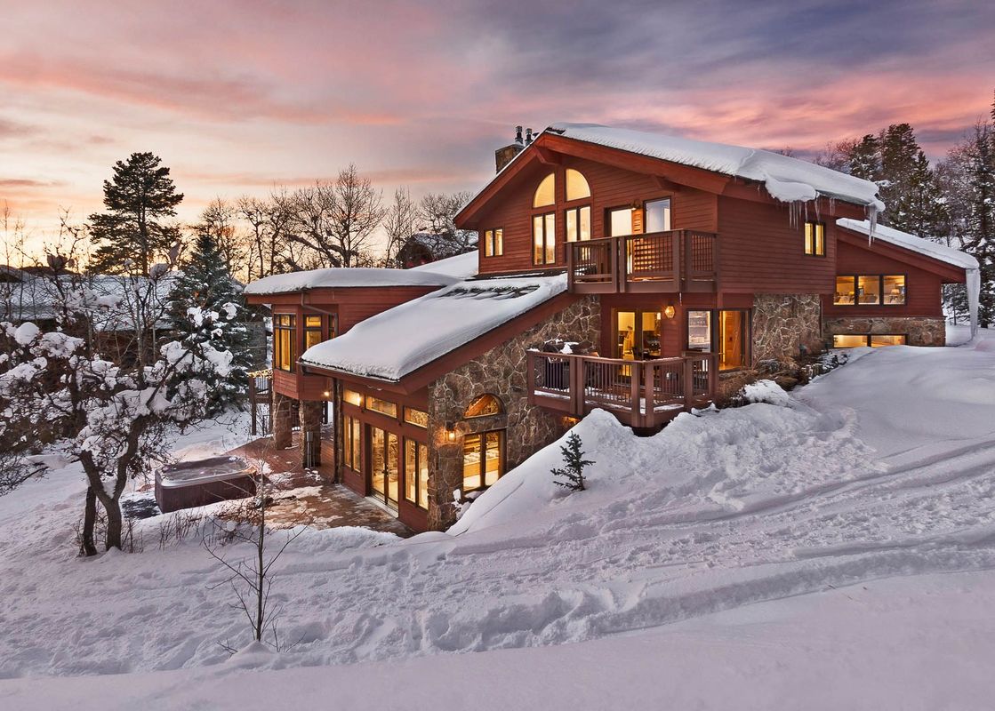 Charming Trails Edge Lodge with snow-covered drive and glowing interiors, a family-friendly option in Steamboat Luxury Rentals on Burgess Creek Road.