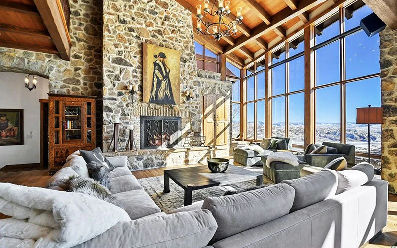 Spacious living room in a Deer Valley luxury rental with stone fireplace, high ceilings, and panoramic alpine views. Spacious living room in a Deer Valley luxury rental with stone fireplace, high ceilings, and panoramic alpine views.