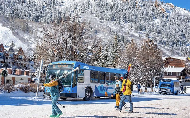 Guests boarding a snowy town shuttle with ski gear in Aspen—convenient transportation near Aspen luxury vacation rentals. Guests boarding a snowy town shuttle with ski gear in Aspen—convenient transportation near Aspen luxury vacation rentals.