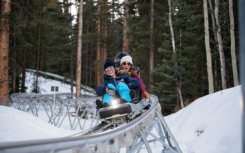 Family enjoying a mountain coaster ride through the forest, showcasing outdoor activities near Aspen luxury vacation rentals. Family enjoying a mountain coaster ride through the forest, showcasing outdoor activities near Aspen luxury vacation rentals.