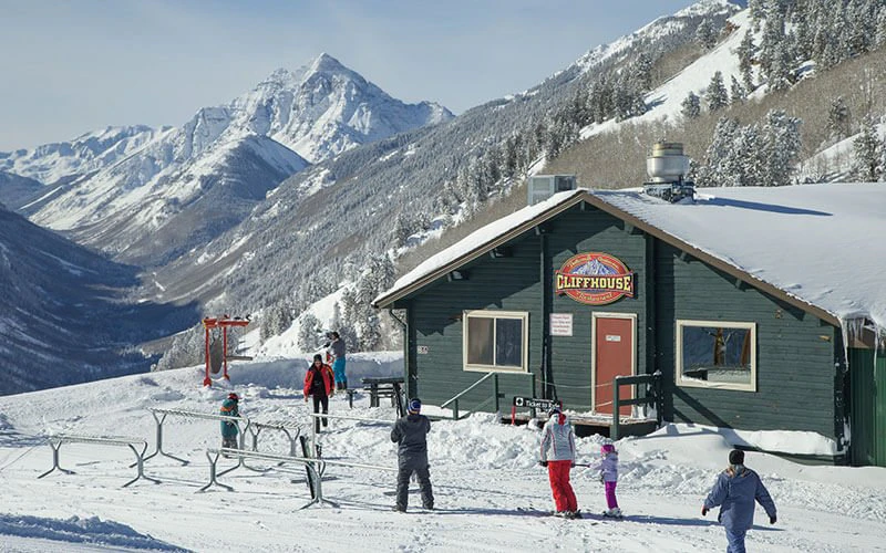 Children playing in snow near ski lodge with mountain backdrop—family-friendly features of Aspen luxury vacation rentals. Children playing in snow near ski lodge with mountain backdrop—family-friendly features of Aspen luxury vacation rentals.