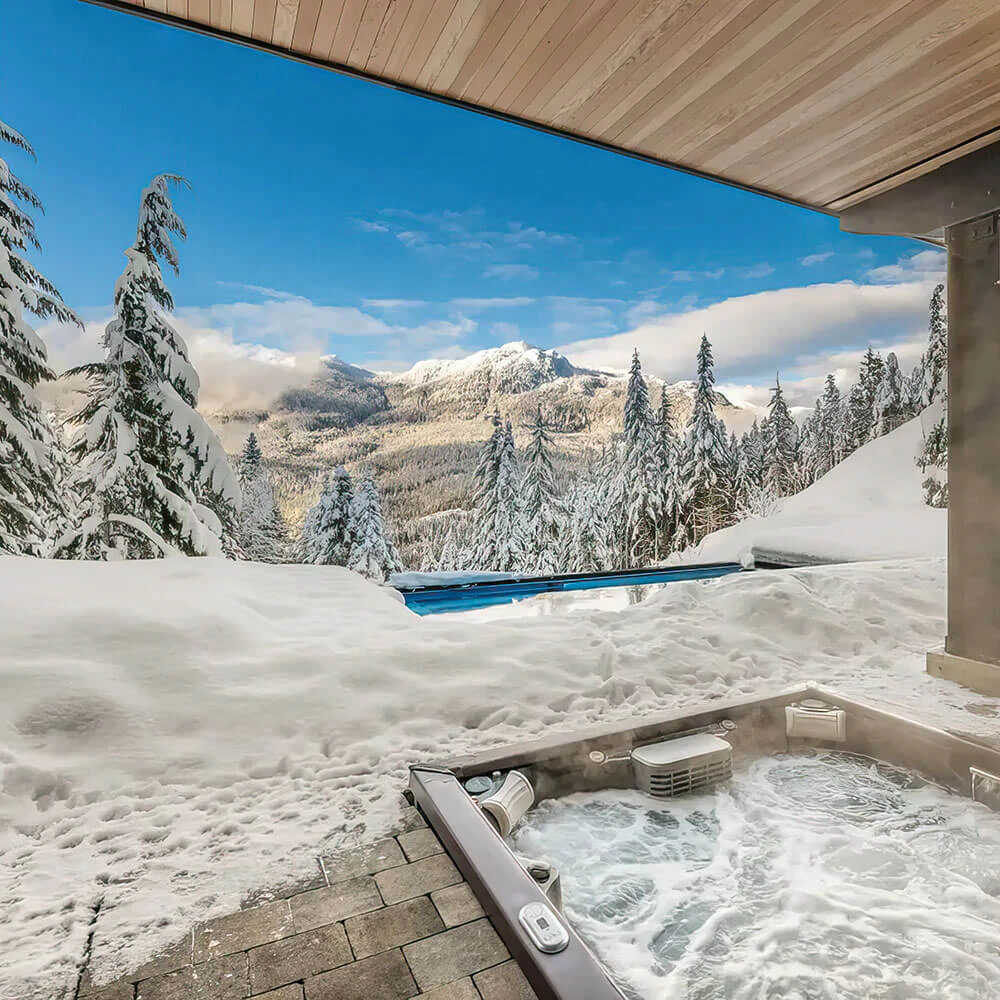 Outdoor hot tub with panoramic snow-covered mountain views at a luxury home in Whistler, part of the Whistler Luxury Rentals collection.